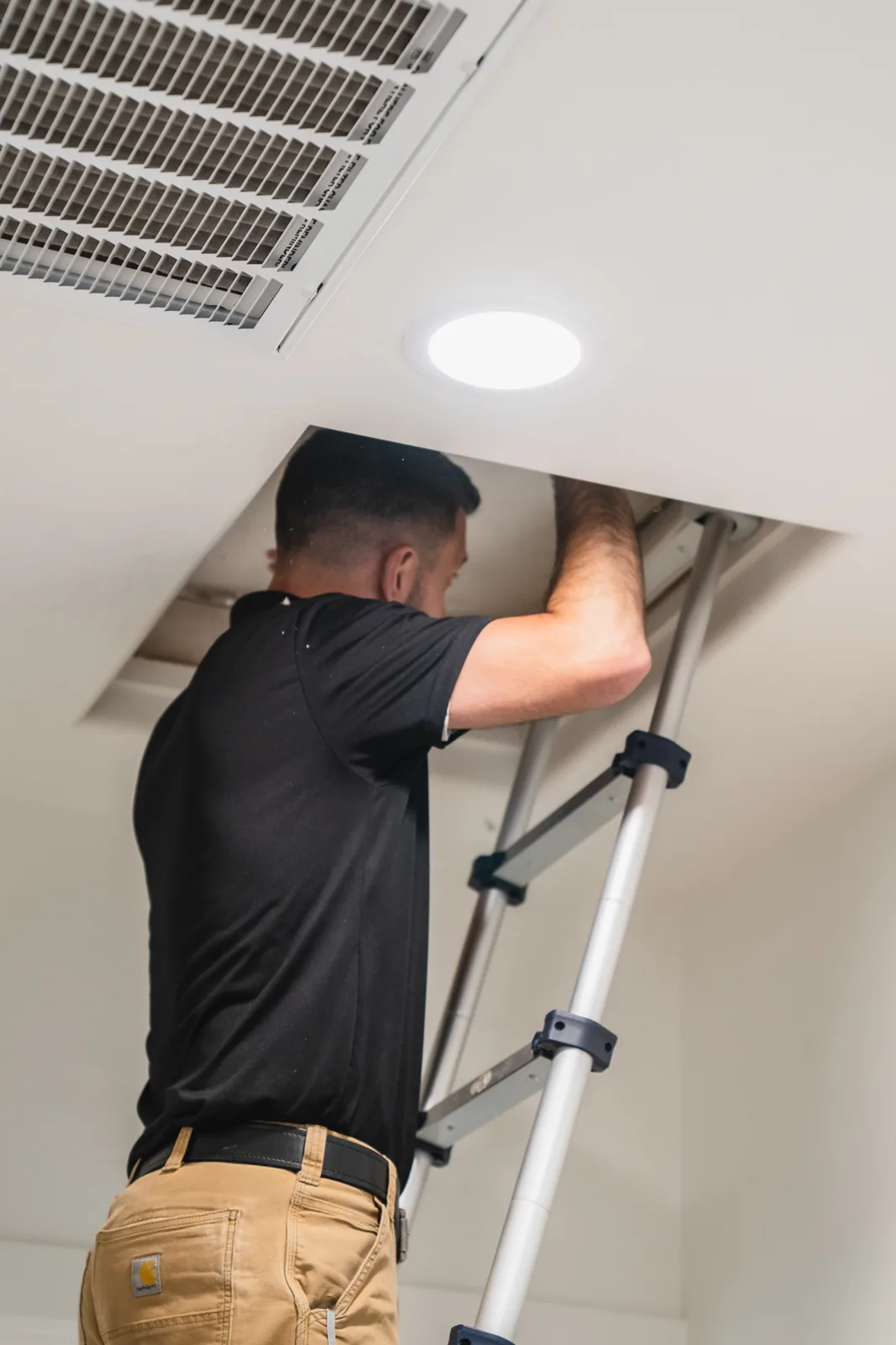 Inspector looking into an attic through a ceiling access hatch