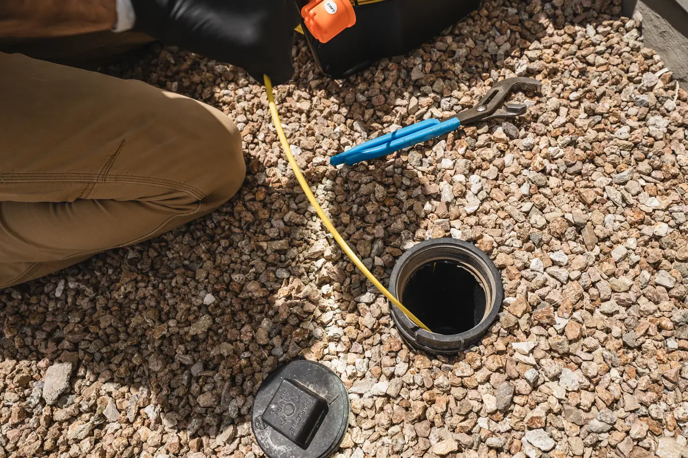 An opened sewer cleanout with a camera line beside it